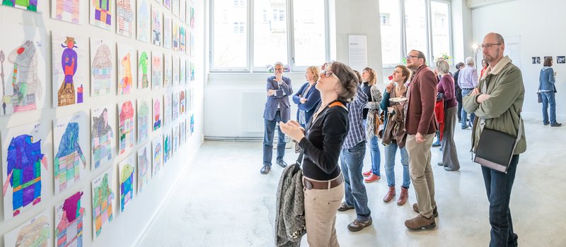 Besucher bei der Ausstellung Zirkus und Jaffa-Krieger betrachten die Zeichnungen an einer Wand