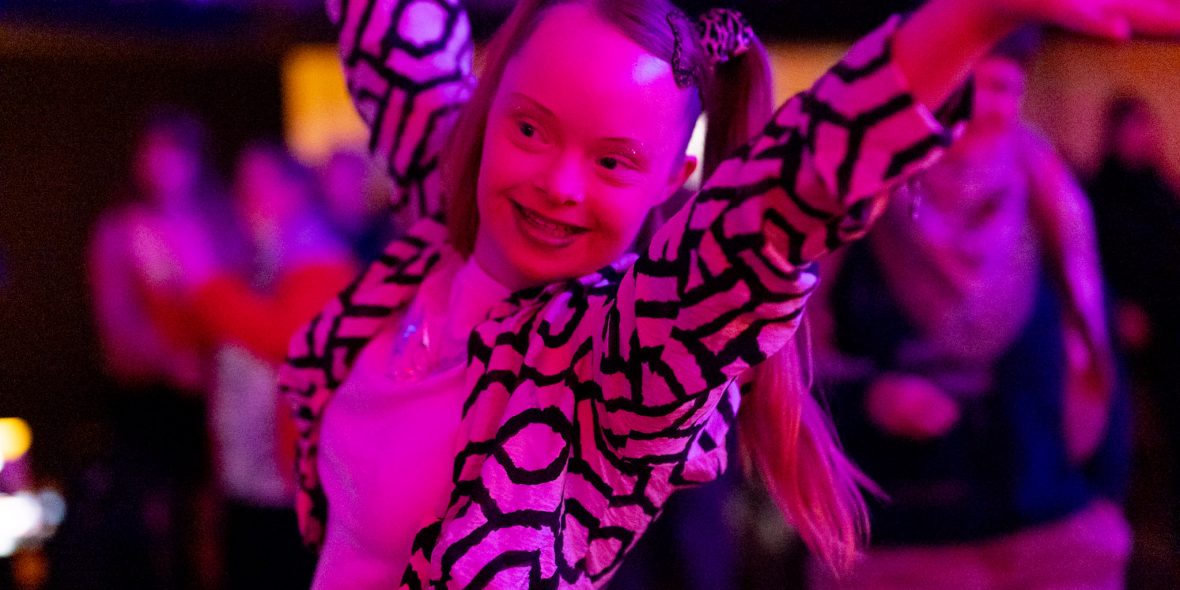 Eine Frau tanzt fröhlich unter pinkem Licht.