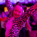 Eine Frau tanzt fröhlich unter pinkem Licht.